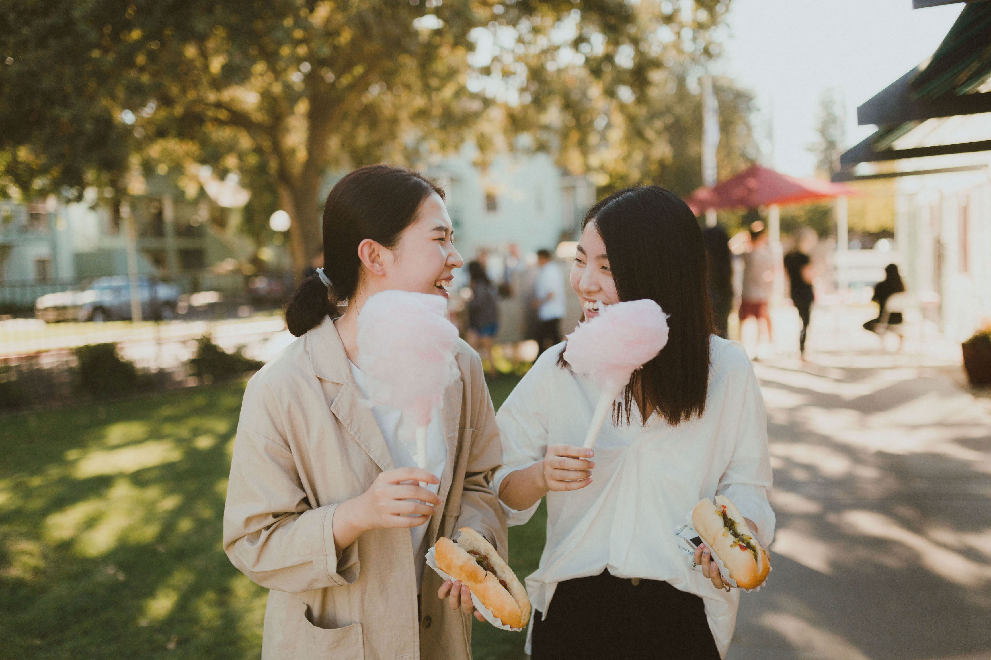 Two young women holding cotton candy and smiling at eachother